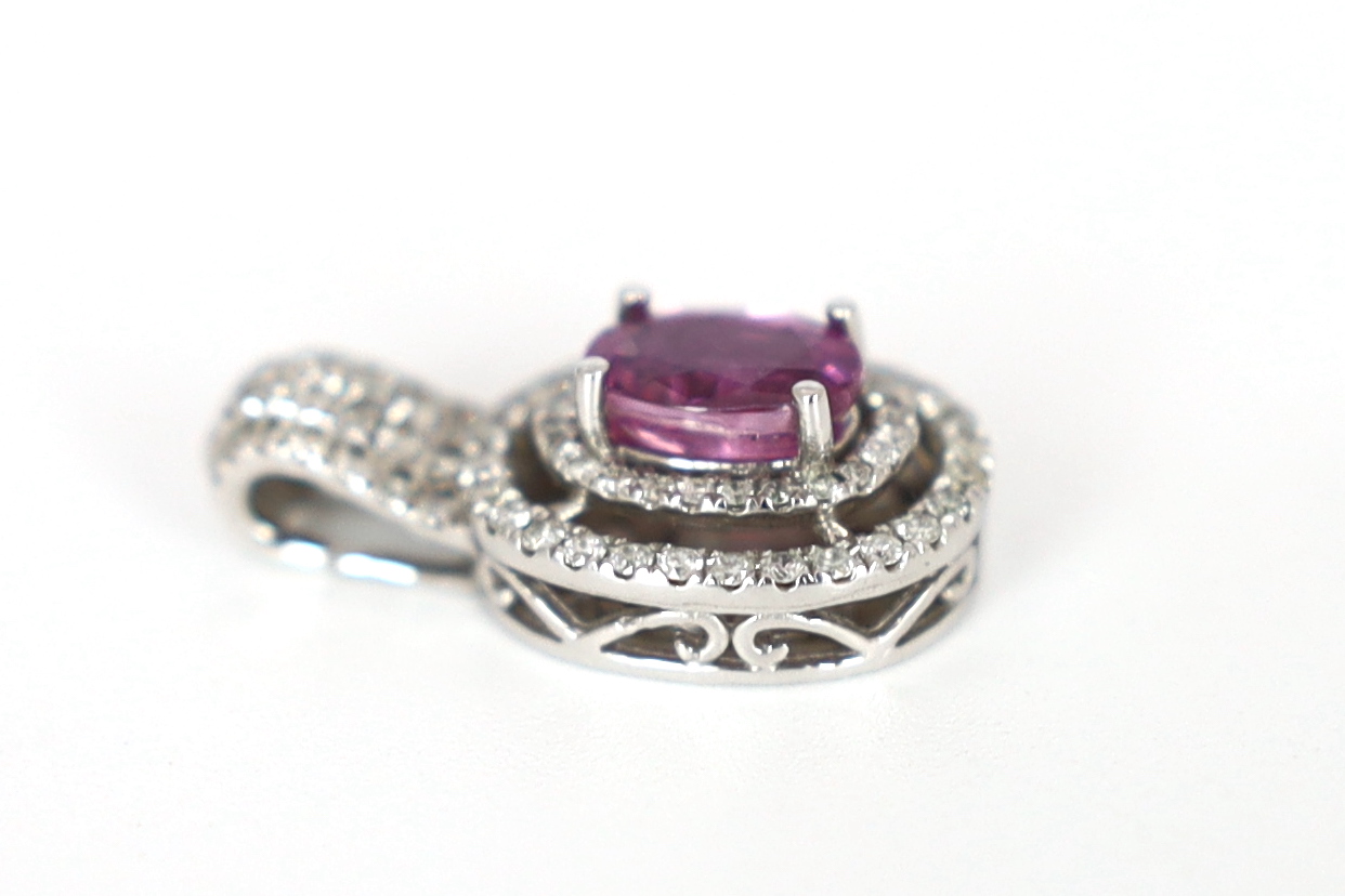 A modern 14ct white gold, pink sapphire and diamond set oval cluster pendant